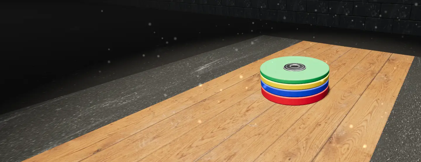 A stack of red, blue, yellow and green bumper plates on the gym floor